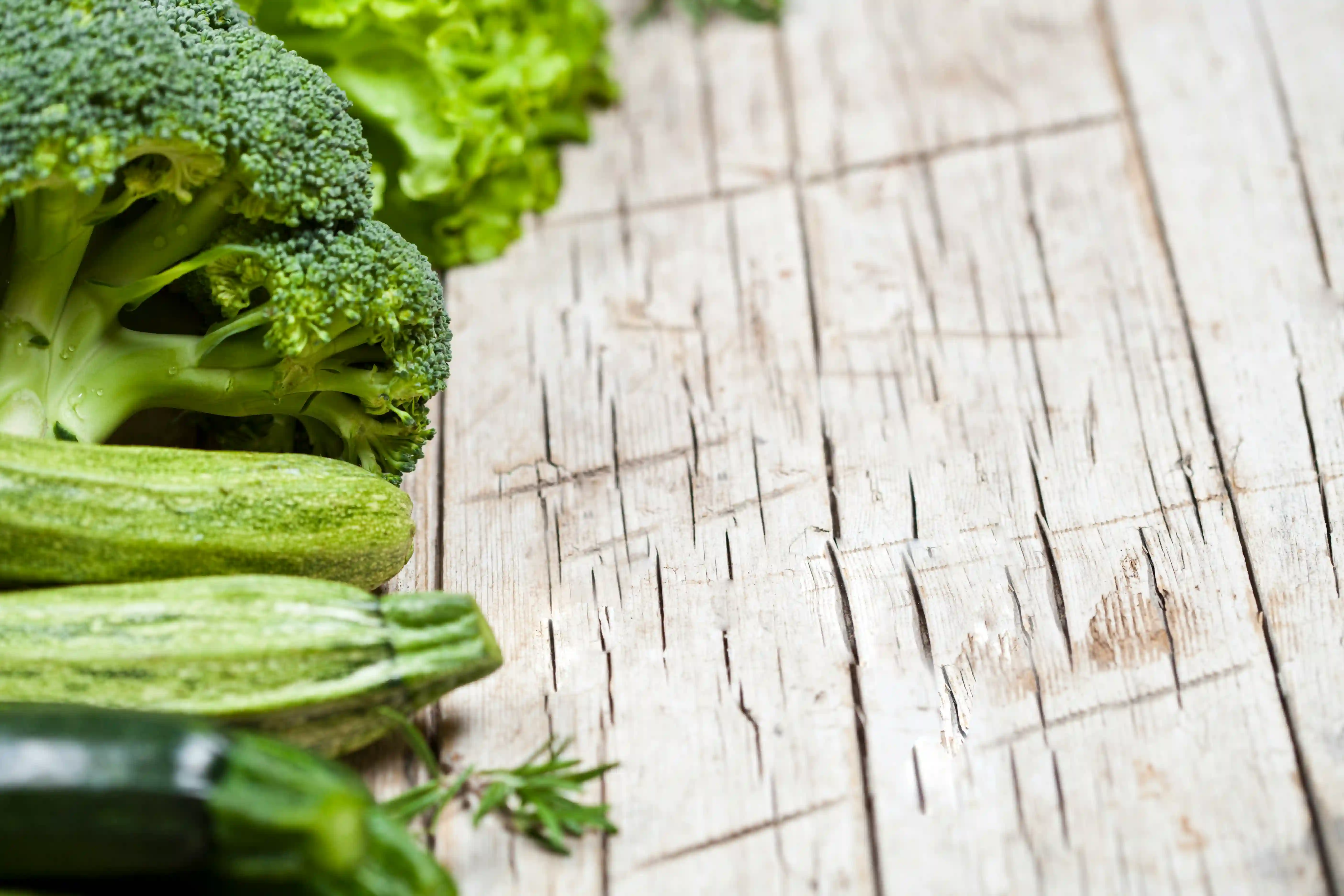 Fresh green vegetables and superfoods arranged on a wooden surface